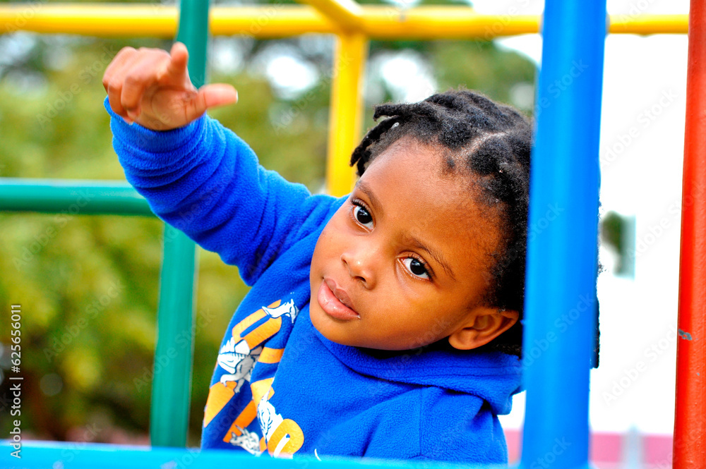 Fototapeta premium beautiful young black African boy with dreadlocks playing in a park .