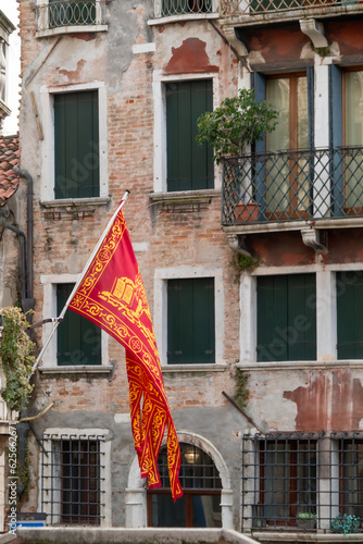 Venetian flag on the streets of Venice, old buildings visible in the background.