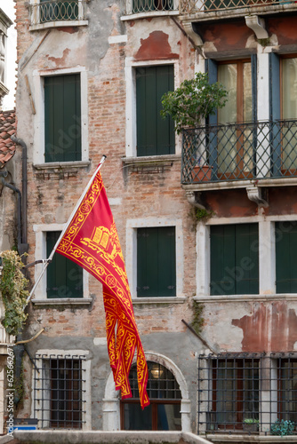 Venetian flag on the streets of Venice, old buildings visible in the background. photo