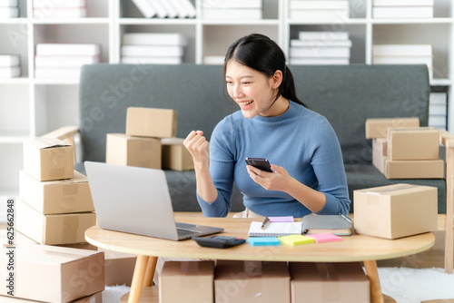 Young business owner woman prepare parcel box and standing check online orders for deliver to customer on tablet, laptop Shopping Online concept.