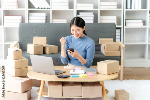 Young business owner woman prepare parcel box and standing check online orders for deliver to customer on tablet, laptop Shopping Online concept.