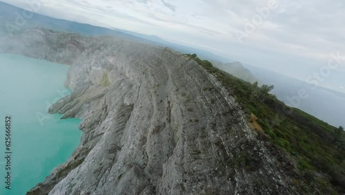 Volcano crater with acidic turquoise lake strolling tourists on edge of cliff aerial view. FPV sport drone captures dynamic footage majestic mountain landscape mountain range breathtaking scenery 4k