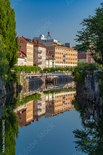 Almost perfect reflection of the buildings in the Ljubljanica river on a sunny summer morning.