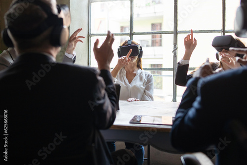 Multicultural Team in VR Business Meeting - Colleagues in an office using VR headsets for a business meeting, gesturing with hands.