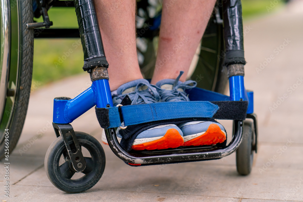 Obraz premium Inclusiveness Close-up of the legs of a man with disabilities who rides a wheelchair in a city park 