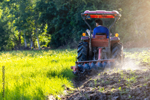 Agricultural workers with tractors Farmer Ploughing a field with tractor preparing in farmland . Farmer in tractor preparing farmland with seedbed for the this year. Agricultural workers with tractors