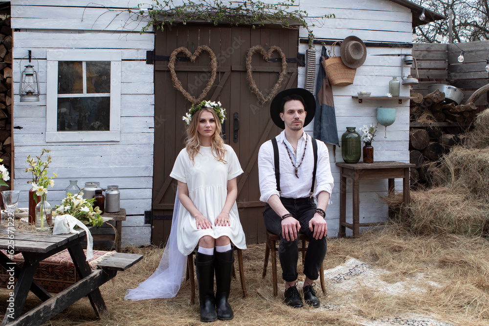 Obraz premium country bride in a white short dress and groom in a white shirt in the village wedding, boho style.