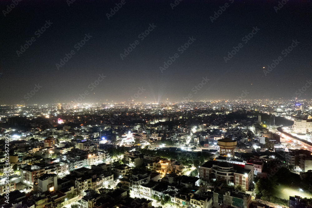aerial drone tripod shot showing cityscape of jaipur delhi with fireworks, rockets, pyrotechnics and sky lanterns at night in celebration of makar sankranti, independence republic day and diwali in In
