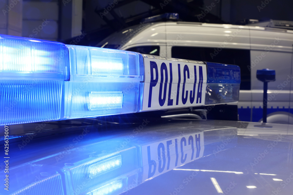 Radiowóz polska policja z Sygnalizator błyskowy niebieski na dachu radiowozu. Alarmowo wieczorem - obrazy, fototapety, plakaty 