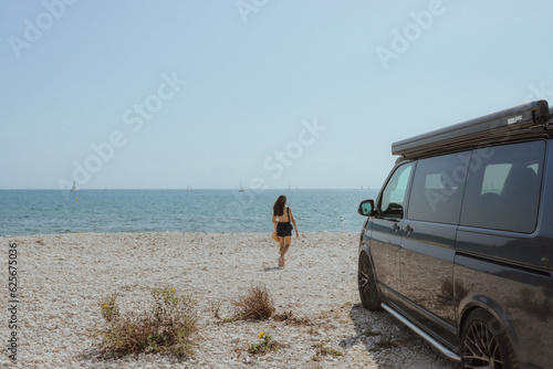 motorhome on the beach, girl walking towards the sea, summer day