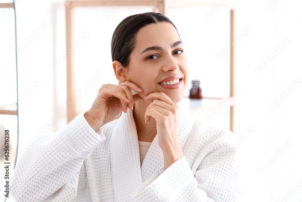 Young woman doing face building exercise in bathroom, closeup Young woman doing face building exercise in bathroom, closeup