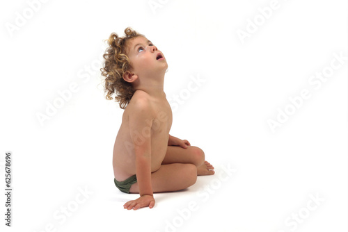 side view of aboy in underpants sitting on the floor looking up on white background (3 year old) photo