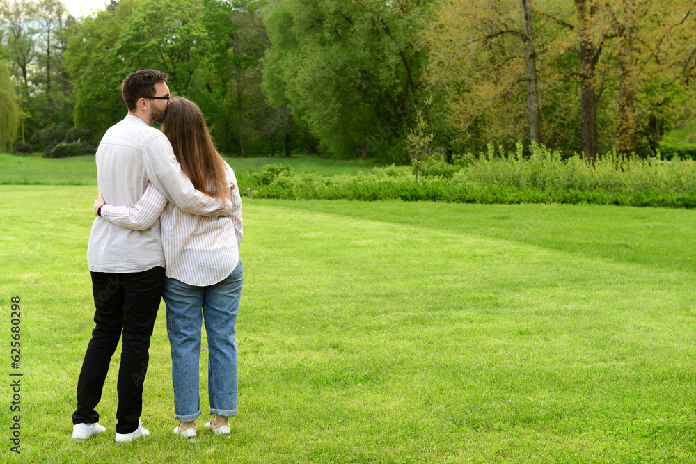 Young man kissing his girlfriend on her head in beautiful park Young man kissing his girlfriend on her head in beautiful park