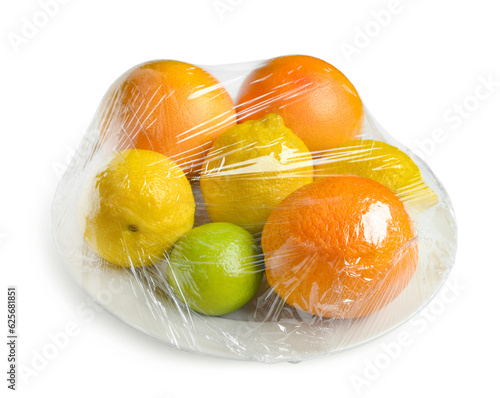 Fototapeta Naklejka Na Ścianę i Meble -  Plastic food wrap with different citrus fruits on white background