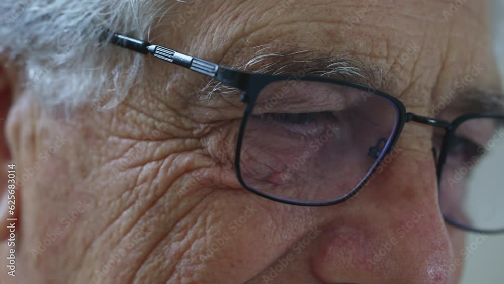 Elderly man close-up eyes with reading glasses. Senior person detail face with wrinkles depicting old age, typing on keyboard off-camera Elderly man close-up eyes with reading glasses. Senior person detail face with wrinkles depicting old age, typing on keyboard off-camera