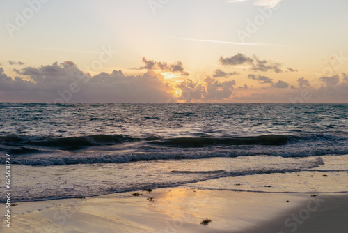 lever de soleil derrière les nuages au dessus de l'océan tel que vu à partir de la plage le matin