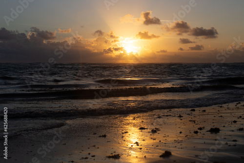 Vue de l oc  an mouvement   lors d un lever de soleil aux lueurs jaunes    partir de la plage