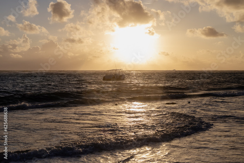 vue d une plage avec la mer devant et quelques bateaux sur l eau lors d un lever de soleil