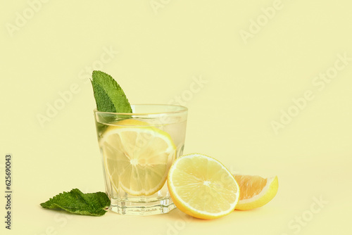 Glass of tasty mojito and lemon on color background