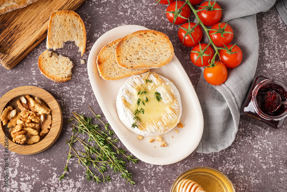 Plate of tasty baked Camembert cheese on grey background Plate of tasty baked Camembert cheese on grey background