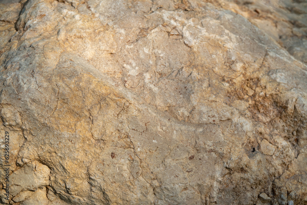 Closeup of the rough stone texture of a rock surface. Beige stone background. Closeup of the rough stone texture of a rock surface. Beige stone background.