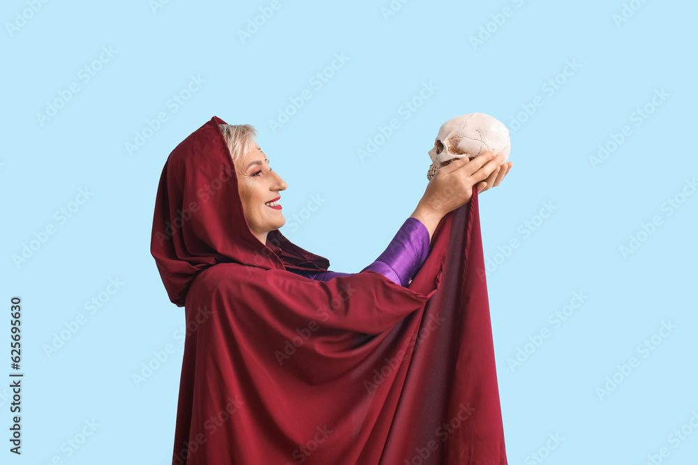Mature witch with human skull on blue background