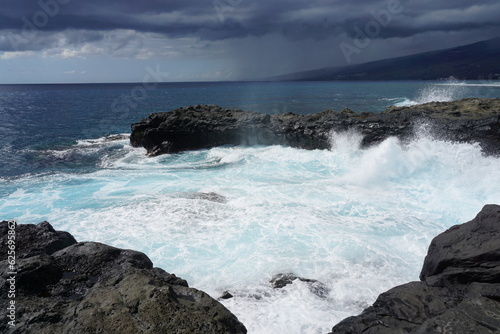 waves crashing on lava rocks on the tropical island of La Réunion, France on a stormy day