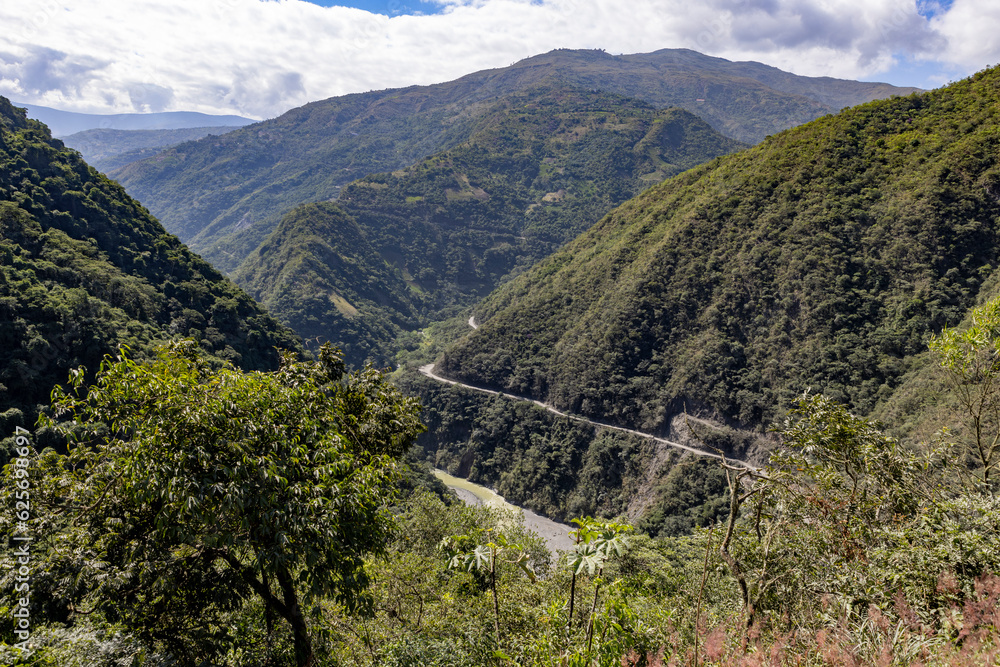 Scenic drive through the remote Bolivian Andes: passing small settlements, forested mountains, rivers and coca plantations on steep hills