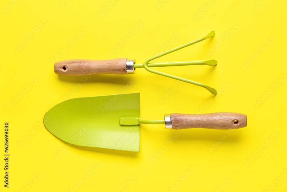 Fototapeta premium Gardening rake and shovel on yellow background