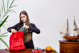 Morning preparation for school. A schoolgirl teenager collects a bag for school, on the table are school supplies lach, which she puts into a bag. Portrait of a beautiful girl with long hair.