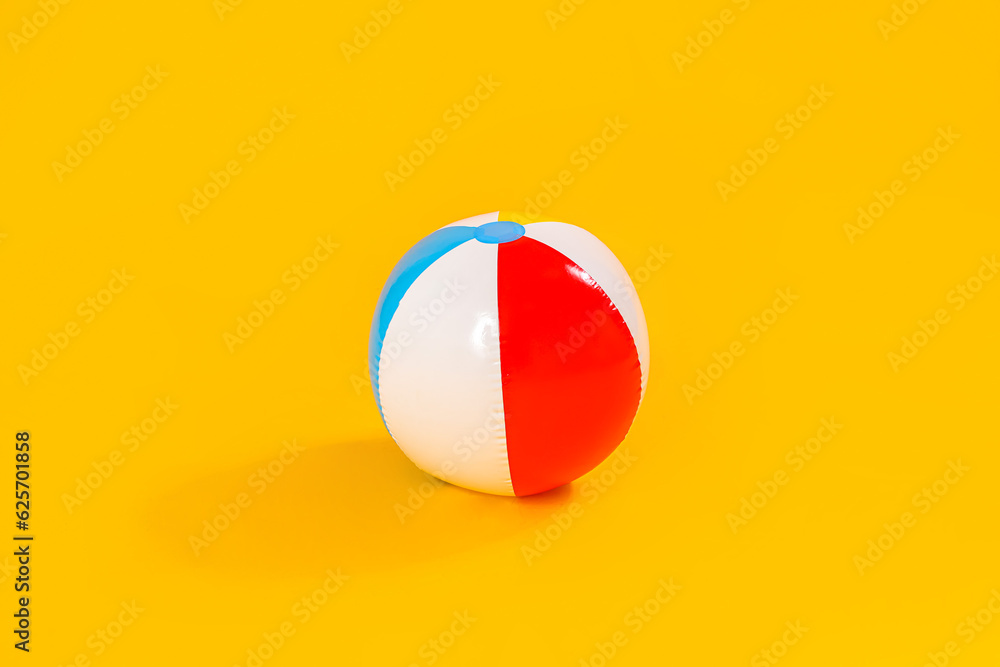 Inflatable beach ball on yellow background