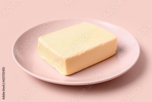 Plate with fresh butter on pink background