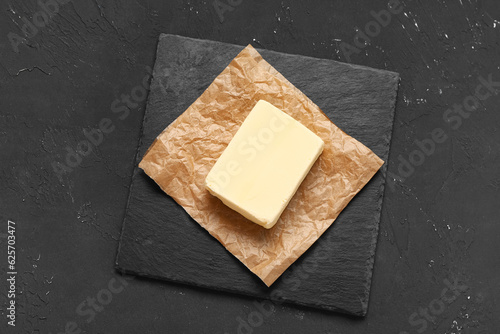 Baking paper with fresh butter on black background
