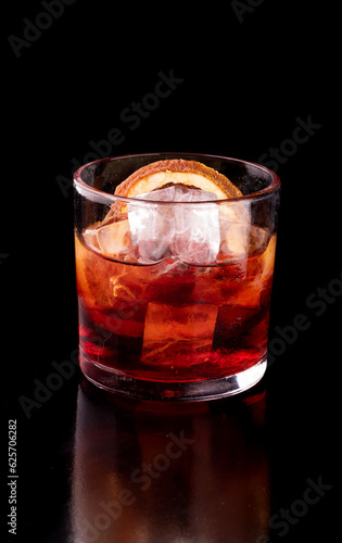 red negroni drink with campari and vermouth on wooden table with orange close-up on black background
