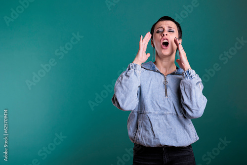 Portrait of angry unhappy woman having agressive emotion screeming while posing in studio standing over isolated background. Stressed worried caucasian female having mental breakdown photo