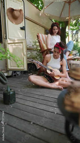 Happy hippie girls are having a good time together with guitar in camper trailer. Holiday, vacation, trip concept. photo