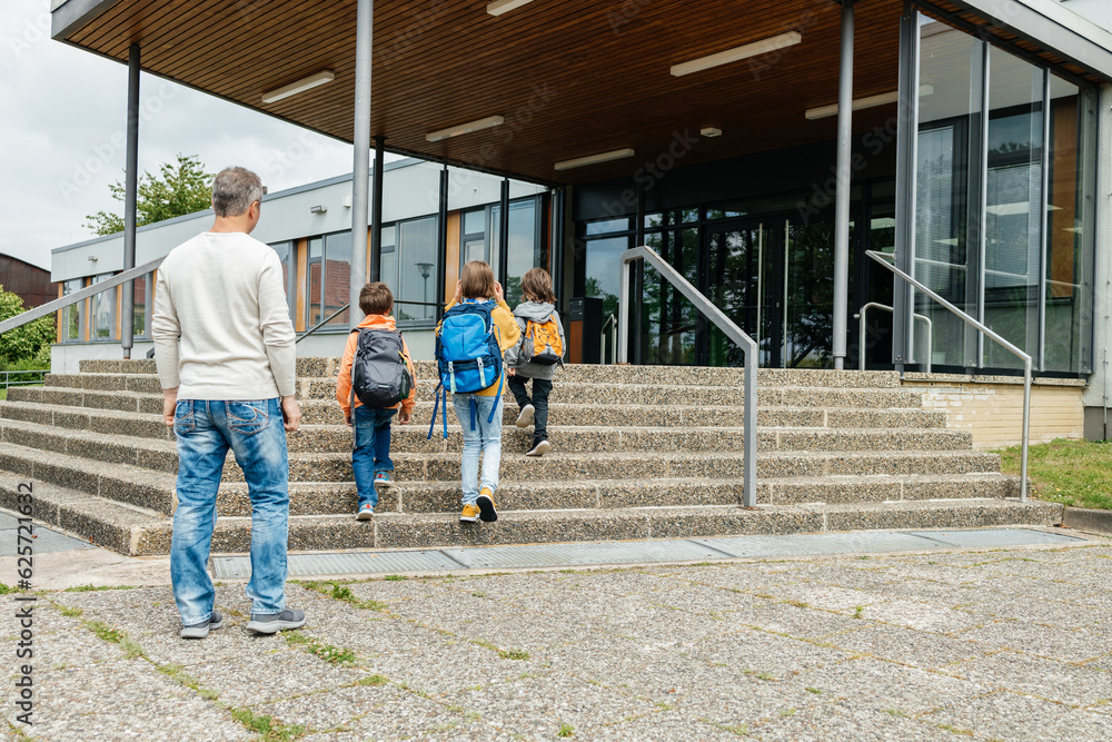 Back to school. A father walks his children to school. Beginning of the school year. Parental care for children. Back to school. A father walks his children to school. Beginning of the school year. Parental care for children.