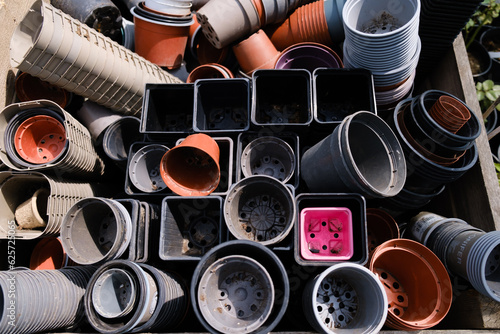Many used plastic flower pots for seedlings and small plants and flowers in a large wooden box