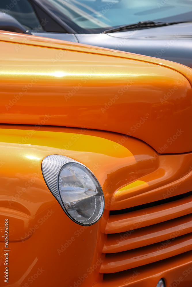 Head lamp of orange classic car close up view.