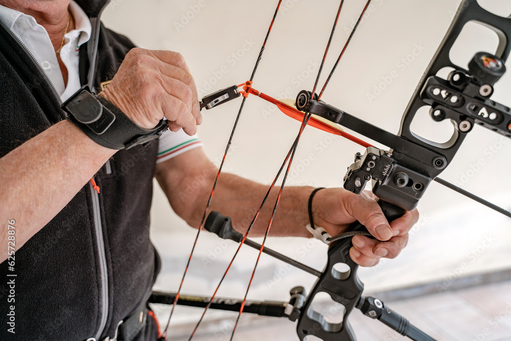 Closeup, selective focus of professional archer preparing bow and arrow for training