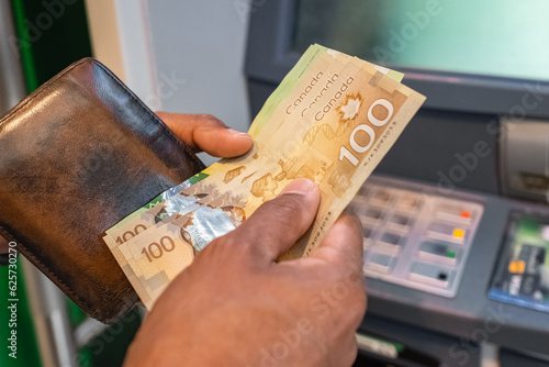 Cash withdrawal at an ATM. Money in the hands of close-up. Canadian dollars banknotes and cash machine. Money in hands photo