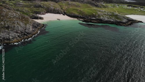 Aerial footage of Achmelvich beach with vibrant green and blue water, white sandy beach and rocky landscape on NC500 route, Scotland photo