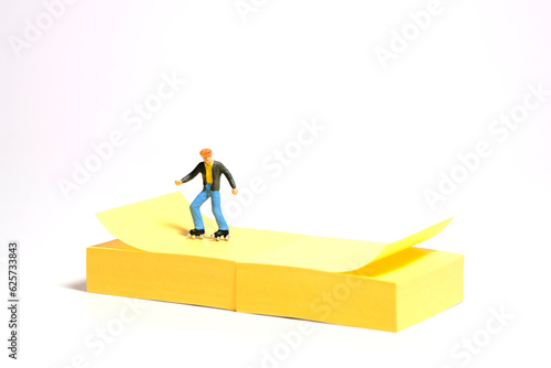 Creative miniature people toy figure photography. Sticky notes installation. A boy roller skater playing at skate park. Isolated on white background