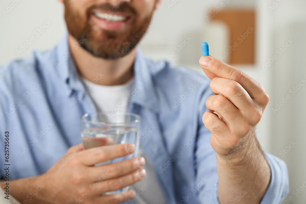Man with glass of water and pill on blurred background, closeup Man with glass of water and pill on blurred background, closeup