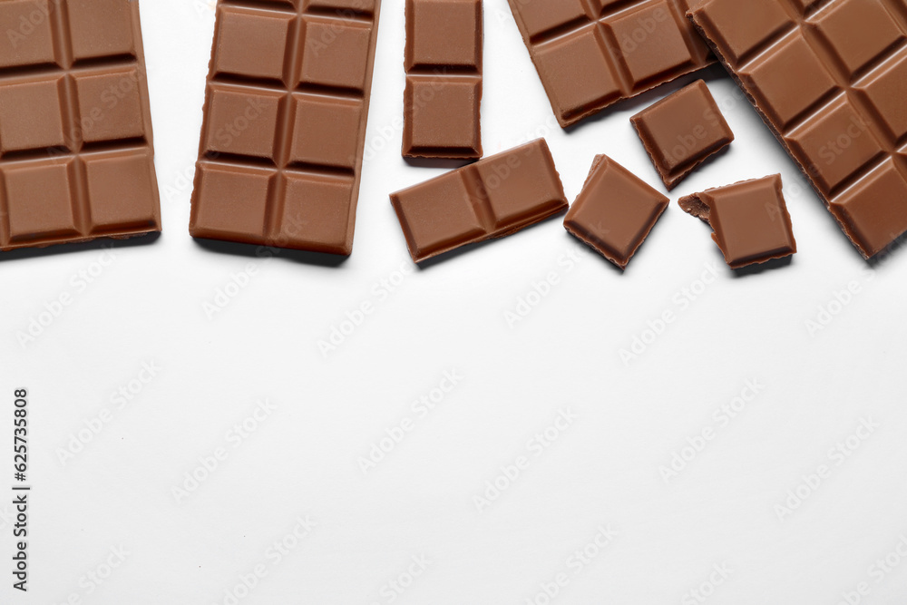 Pieces of delicious chocolate bar on white background, flat lay. Space for text Pieces of delicious chocolate bar on white background, flat lay. Space for text