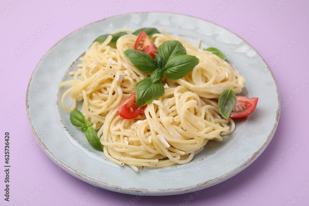 Delicious pasta with brie cheese, tomatoes and basil leaves on violet background, closeup Delicious pasta with brie cheese, tomatoes and basil leaves on violet background, closeup
