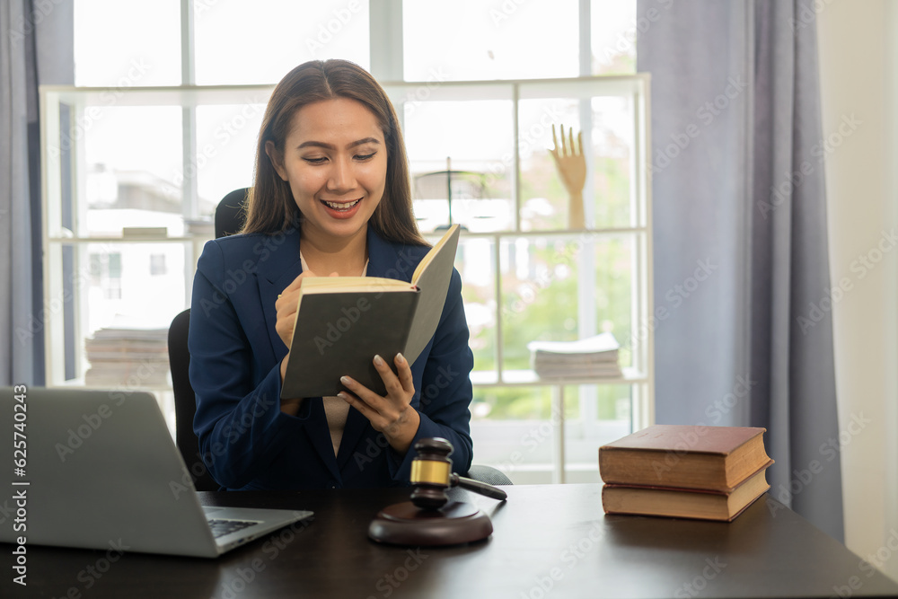 A young Asian female lawyer who works with contracts on laptops in justice law firms and courtroom legal concepts on wooden tables and counsel or legal counsel, justice advice and concepts. A young Asian female lawyer who works with contracts on laptops in justice law firms and courtroom legal concepts on wooden tables and counsel or legal counsel, justice advice and concepts.