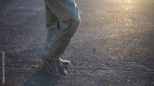 Legs of a Fighter Pilot or Combat Pilot Walking at Sunset in the Air Base. Low Angle View. 4K Resolution.