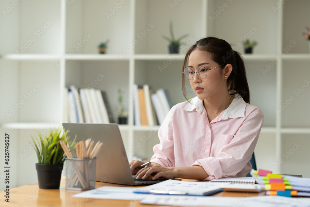 Cropped image of asian businesswoman analyzing paperwork using laptop to actively search for information tense expressions at the office. Cropped image of asian businesswoman analyzing paperwork using laptop to actively search for information tense expressions at the office.