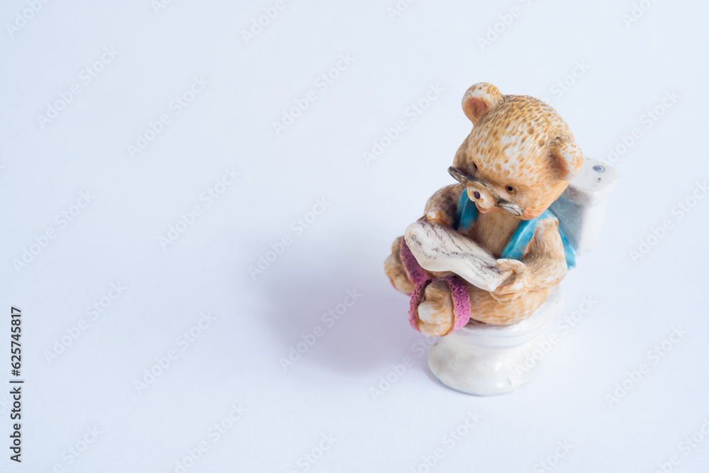 Happy bear in porcelain glasses reads the newspaper in the bathroom, quiet moment over the toilet Happy bear in porcelain glasses reads the newspaper in the bathroom, quiet moment over the toilet